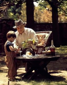 an old man sitting on a bench next to a little boy