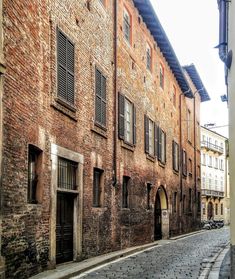 an old brick building with shuttered windows on the side and cobblestone street