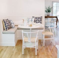 a table and chairs in a room with white walls, wood floors and wooden flooring