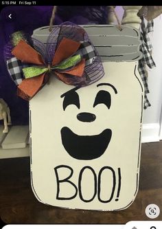 a wooden sign with a face painted on it and a bow hanging from the front