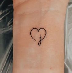 a small heart tattoo with an arrow in the middle and a musical note on it