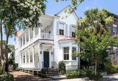 a large white house with trees and bushes around it