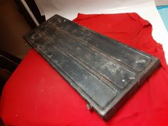 an old metal cutting board sitting on top of a red tablecloth covered table cloth