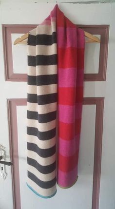 two towels hanging on a door hanger in front of a white door with pink and black stripes