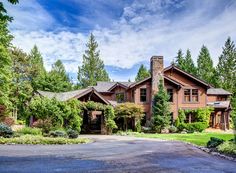 a large house with lots of trees and bushes on the side of the road in front of it