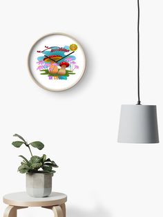 a clock that is on the wall next to a table with a potted plant