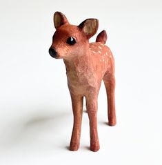 a small toy deer standing on top of a white surface