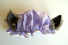 a stuffed animal wearing a purple dress with flowers on it's head and ears