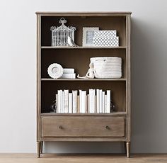 an old bookcase with books and other items on the top shelf, against a white wall