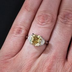 a close up of a person's hand with a yellow and white diamond ring