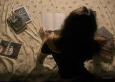 a woman laying in bed reading a book next to an open book on top of her