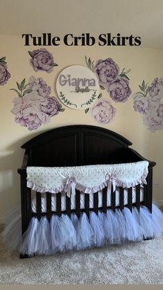 a baby crib with flowers on the wall and tulle skirted bedding