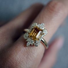 a close up of a person's hand with a yellow and white diamond ring