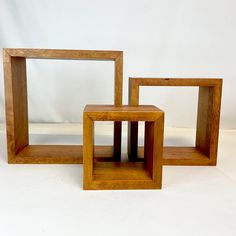 three wooden frames sitting next to each other on top of a white surface with no one in it