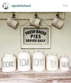 four white canisters sitting on top of a wooden table next to a sign that says fresh baked pies served daily