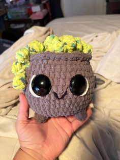 a crocheted planter with eyes and hair is shown in front of a bed