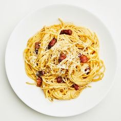 a white plate topped with spaghetti and bacon