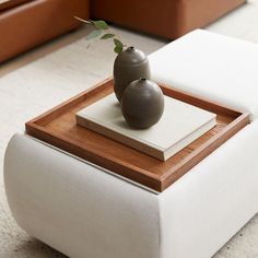 two vases sitting on top of a white ottoman