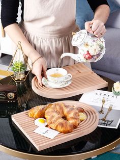 the woman is pouring tea into her cup and plate with pastries on it,