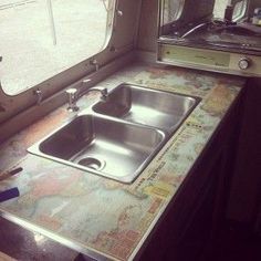 a kitchen with a sink, stove and window looking out onto the street in front of it