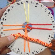 a person is holding up a piece of paper with numbers on it and thread in the middle