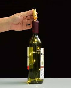 a hand is holding a wine bottle with lights on it