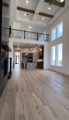 a large open floor plan with wood floors and white walls, two balconies on the second story