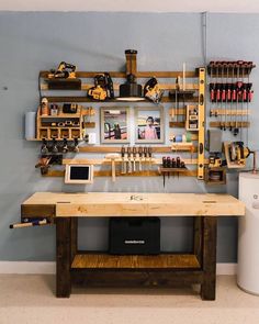 a workbench with tools on the wall and shelves filled with various items in it