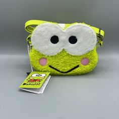 a small yellow purse with eyes on it and a book next to it, sitting on a gray surface