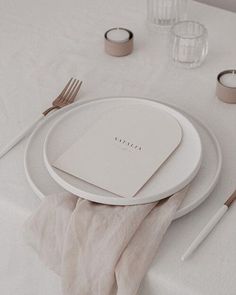 a white table setting with napkins, silverware and place settings on the table