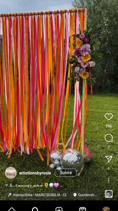 an orange and pink streamer is hanging from the side of a pole with flowers on it