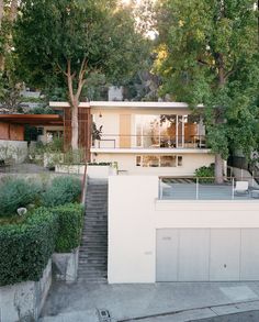 an instagram photo of a house with trees and bushes in the foreground, on which there is a staircase leading up to it