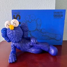 a blue figurine sitting on top of a wooden table next to a book