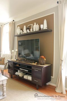 a flat screen tv sitting on top of a wooden entertainment center in a living room