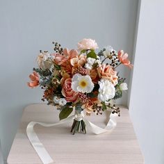 a bouquet of flowers sitting on top of a wooden table next to a white ribbon