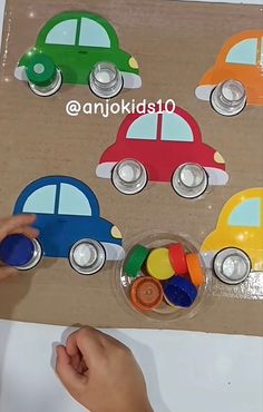 a child's hand is playing with magnets on a piece of cardboard that has cars in it