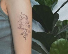 a woman with a tattoo on her arm next to a potted plant and green leaves