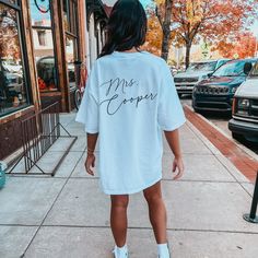 a woman is walking down the sidewalk wearing a t - shirt that says miss cooper