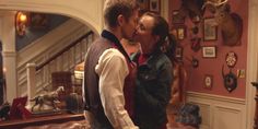 a man and woman kissing in a living room with antlers on the wall behind them