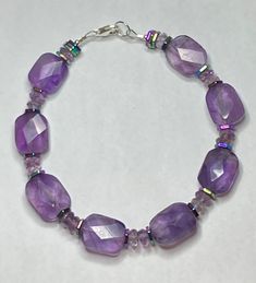 Amethyst Purple Bracelet with Iris Hematite beads * Large High Quality rectangular     faceted Amethyst stones * Amethyst roundel beads * Iris Hematite stone multi toned     hexagon beads * Sterling Silver Lobster claw clasp * Lg. sterling silver O ring for easily     attaching clasp.  * Makes a great gift for your mom,     wife, sister or daughter. Spiritual Faceted Purple Beaded Bracelets, Spiritual Purple Faceted Beaded Bracelets, Purple Amethyst Faceted Beaded Bracelets, Faceted Purple Amethyst Beaded Bracelets, Purple Faceted Amethyst Beaded Bracelets, Purple Amethyst Beaded Bracelets With Polished Beads, Purple Rondelle Beaded Gemstone Bracelets, Purple Faceted Spiritual Bracelets, Faceted Purple Beaded Bracelets