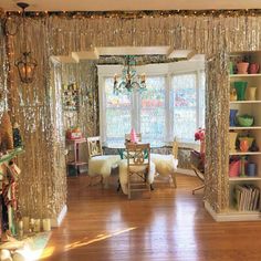 a living room filled with furniture next to a window covered in sequins and lights