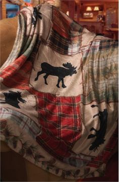 a plaid blanket with moose silhouettes on it is draped over a couch in a living room