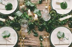 an overhead view of a table set with place settings and greenery on the plates