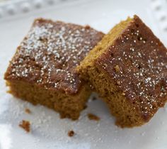 two pieces of brownie sitting on top of a white plate with powdered sugar