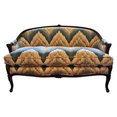 an old fashioned couch is upholstered with gold and blue fabric on the back