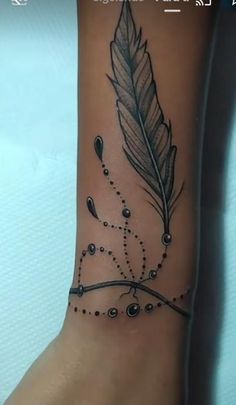 a tattoo with a feather and beads on it