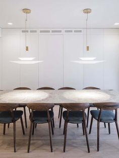 a dining table with six chairs and two pendant lights hanging from it's ceiling