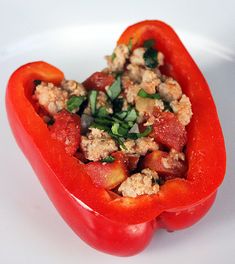 a close up of a red pepper with meat and vegetables in it on a white plate