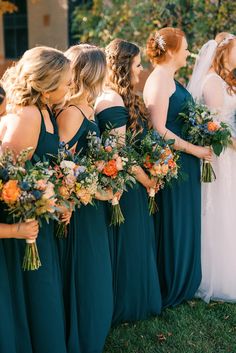 a group of women standing next to each other wearing green dresses and holding bouquets