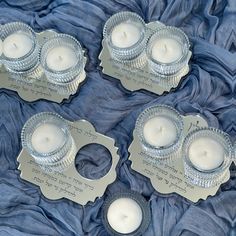 three silver candles sitting on top of a blue cloth